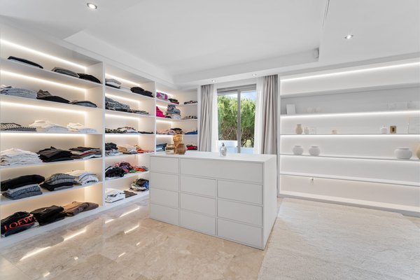 Garderoba urządzona jak butik — podświetlane półki na torebki i buty