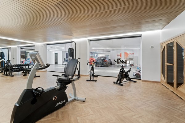 Prywatna siłownia z lustrzaną ścianą, sprzętem cardio i wejściem do sauny