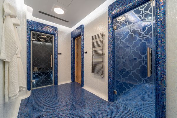 Hammam w strefie spa wyłożony granatową mozaiką, obok przeszklona kabina